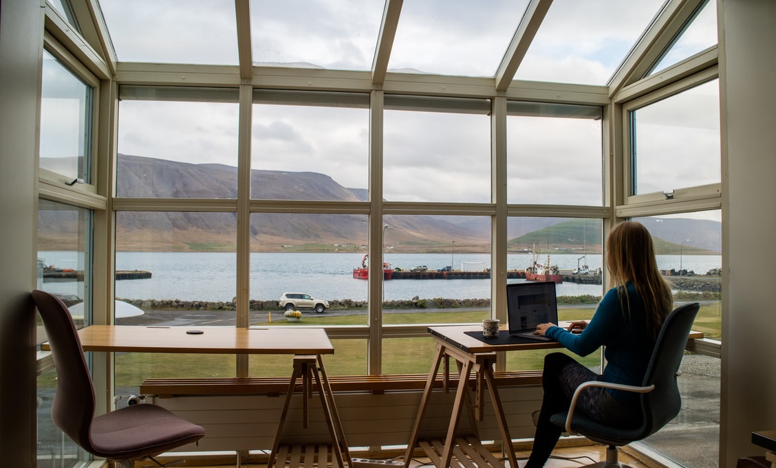 A woman working at home with panorama widndows. Looks like it's Iceland or somewhere north