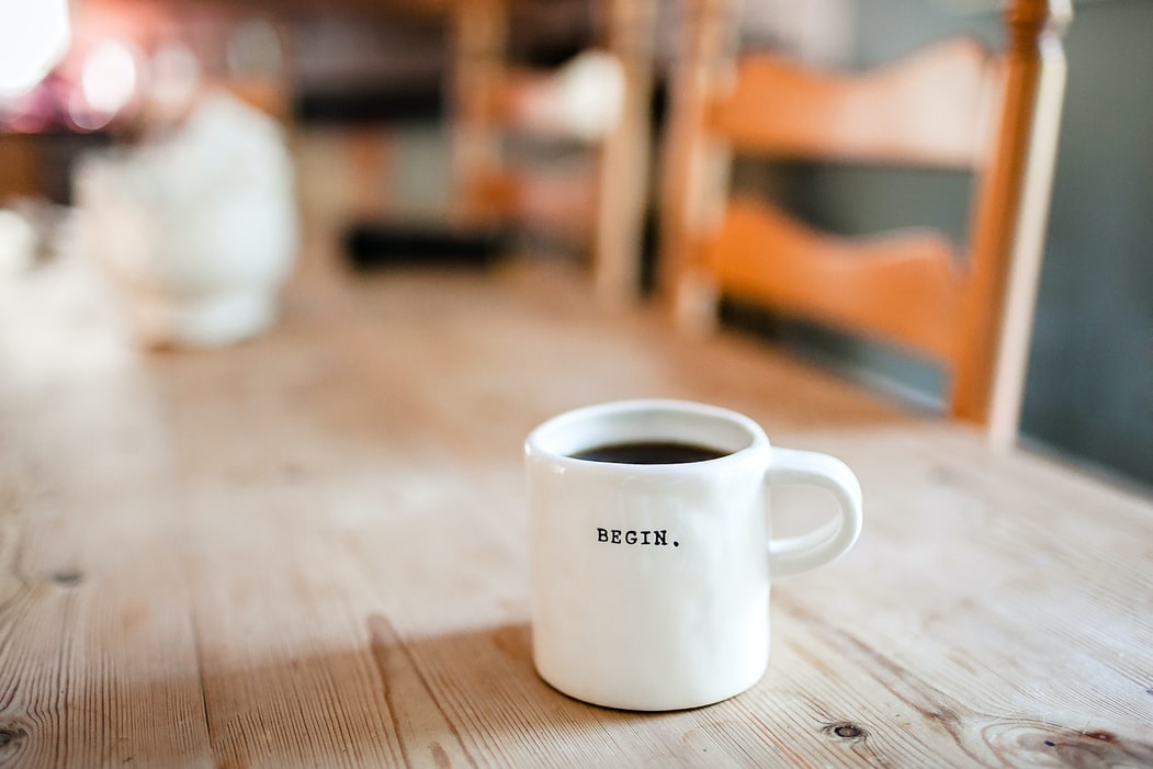 A cup of coffee with "BEGIN." caption written on it