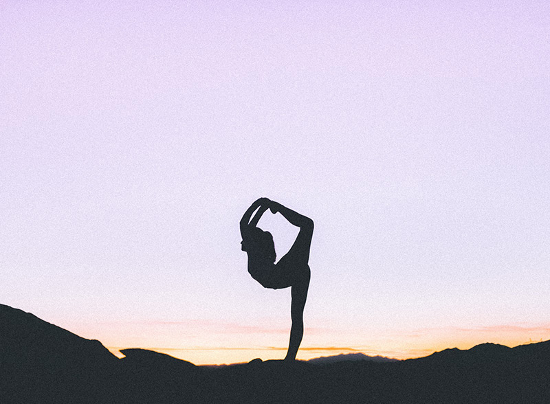 A siluette of a woman stratching at the sunset