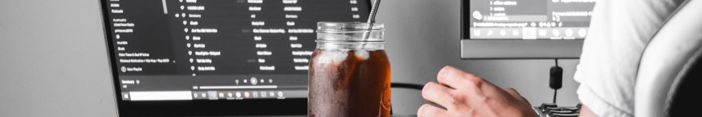 Two computer screens with a huge iced coffee